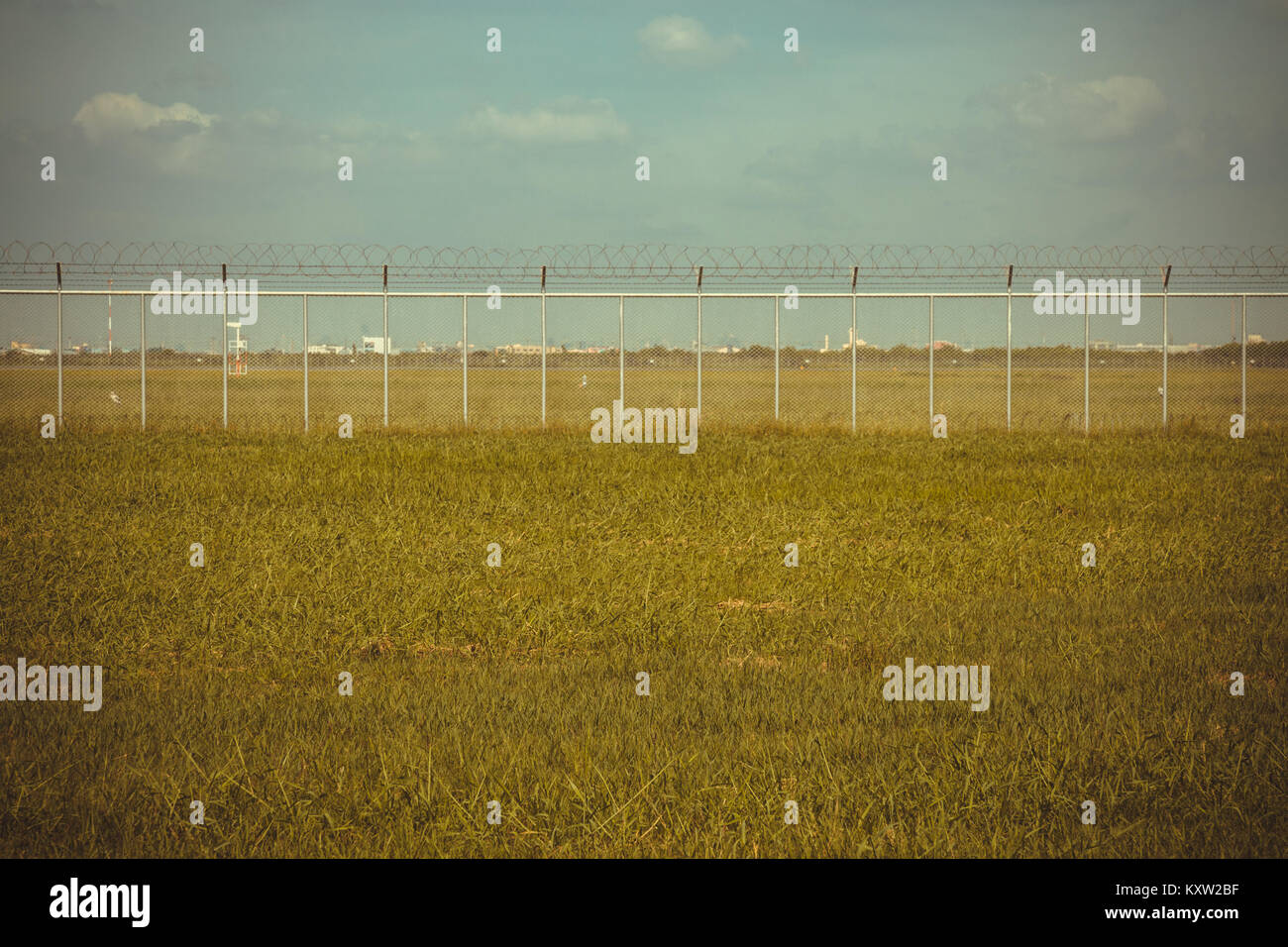 green field and barbed wire fence in jail or security zone, vintage photo and film style Stock Photo