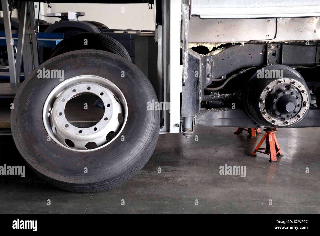 bus spare wheel tire waiting to change and axle bus on the lifting jack at the garage Stock Photo