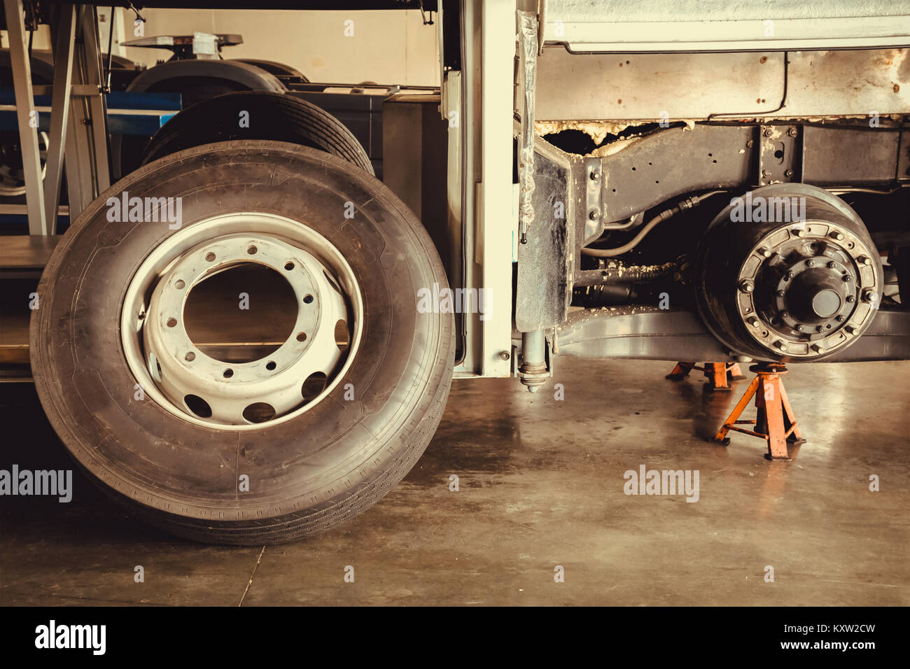 bus spare wheel tire waiting to change and axle bus on the lifting jack at the garage, vintage photo and film style Stock Photo