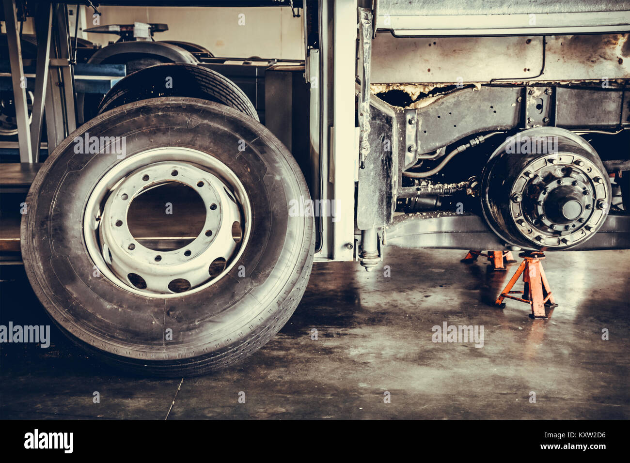 bus spare wheel tire waiting to change and axle bus on the lifting jack at the garage, low key photo and dramatic style Stock Photo