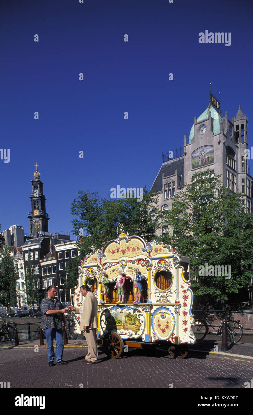 The Netherlands. Amsterdam. Street organ called De drie pruiken, built in 1905. Organist collecting money from passer-by. Stock Photo
