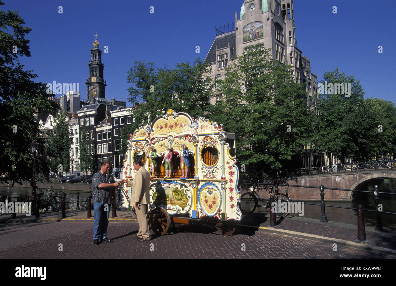 The Netherlands. Amsterdam. Street organ called De drie pruiken, built in 1905. Organist collecting money from passer-by. Stock Photo