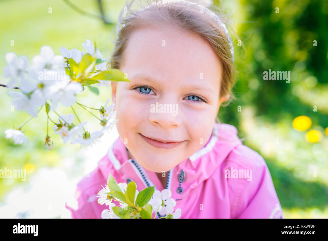 little laughing girl in pink jacket squinting eyes on a spring
