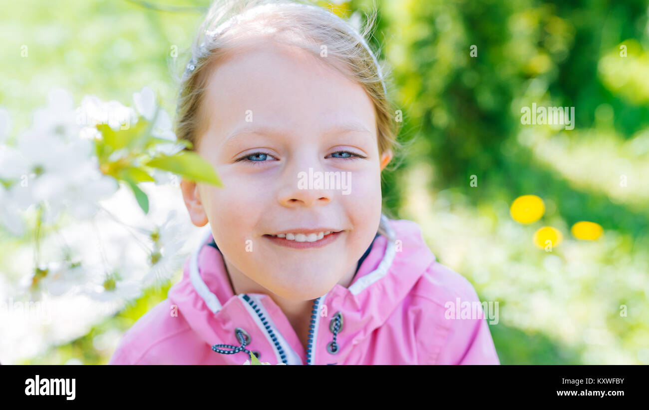 little laughing girl in pink jacket squinting eyes on a spring