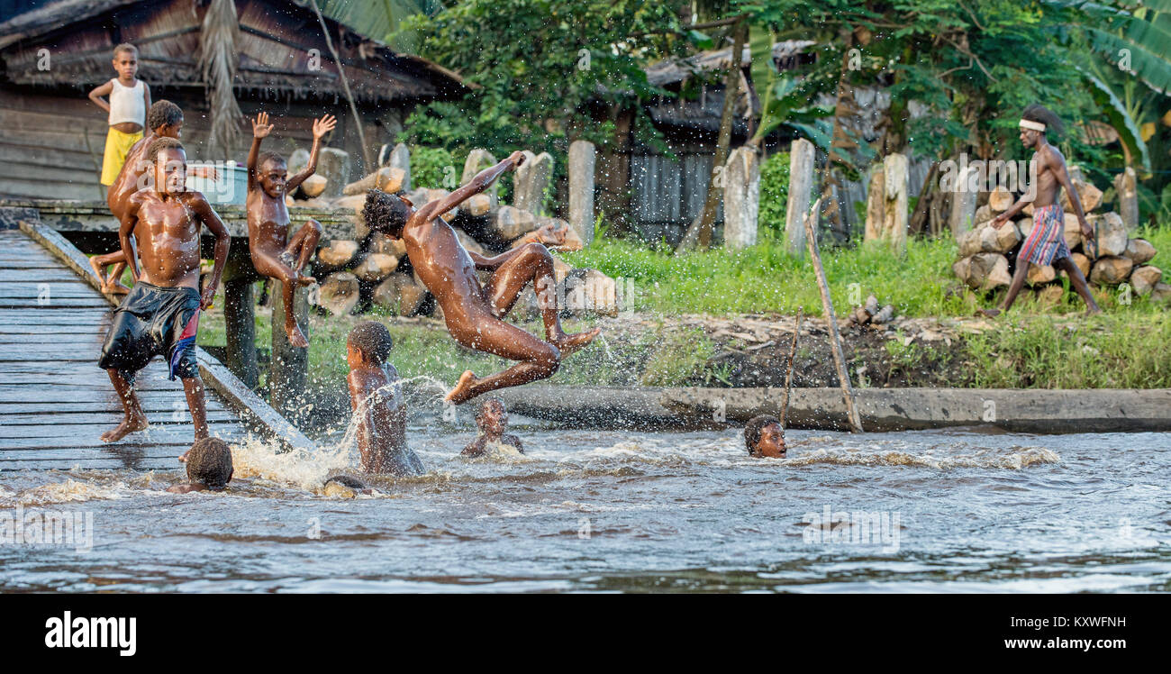 Noisy fun kids. Children of the tribe of Asmat people bathe and swim in the river. New Guinea.May 23, 2016 Stock Photo