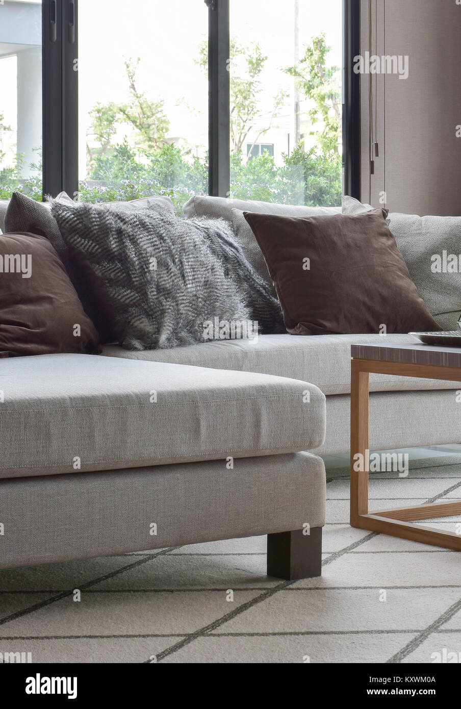 Brown and gray pillows on beige sofa in modern living room Stock Photo ...