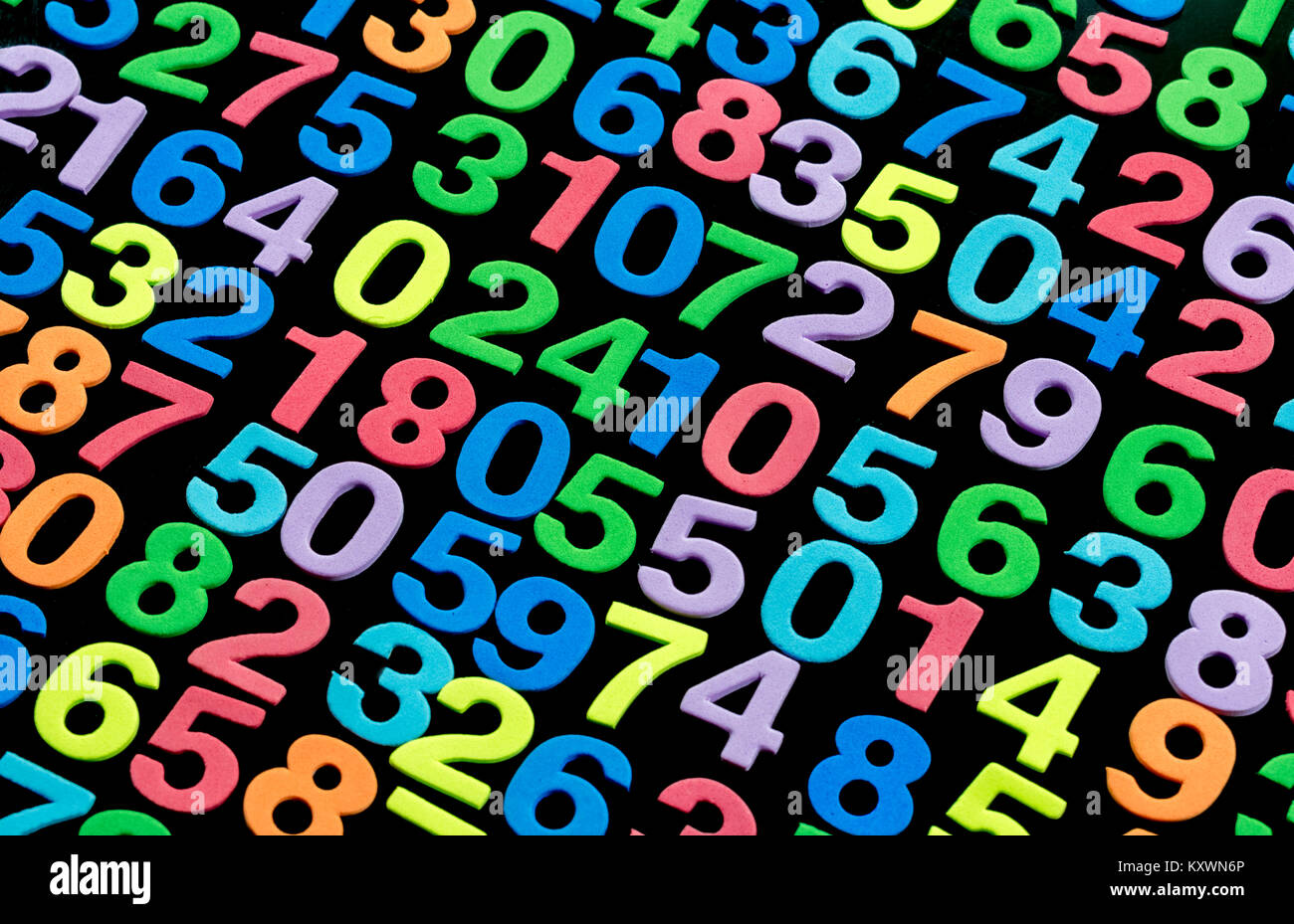 Multiple rows and columns , diagonals of foam cut colored numbers in random order , against a black background Stock Photo