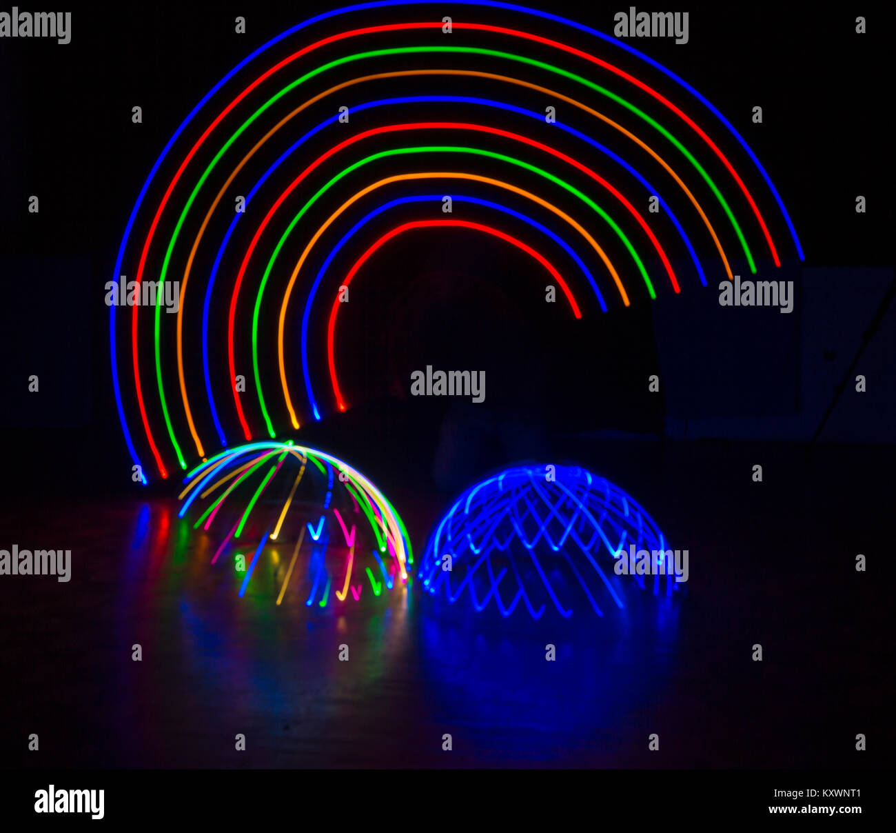 multi-coloured light trails patterns in shape of arc rainbow above multi-coloured and blue light domes - abstract painting with light, light painting Stock Photo