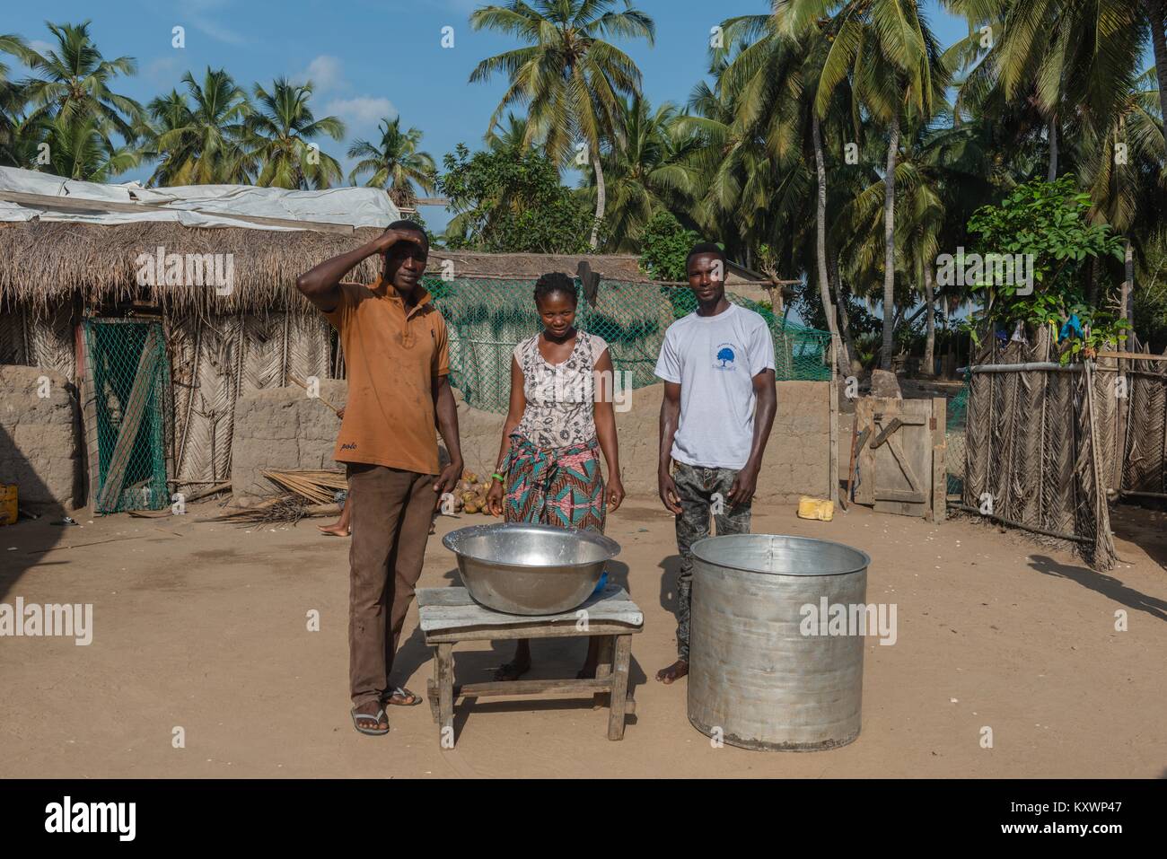 Pastor Thomas Thompsoni (left) is an oil producer on Aziza Island. The photo shows him with his wife and a farmhand. Production of coconut oil,Aziza I Stock Photo