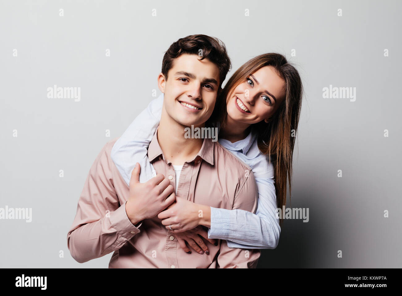 Portrait of a cheerful young couple hugging while standing and looking ...