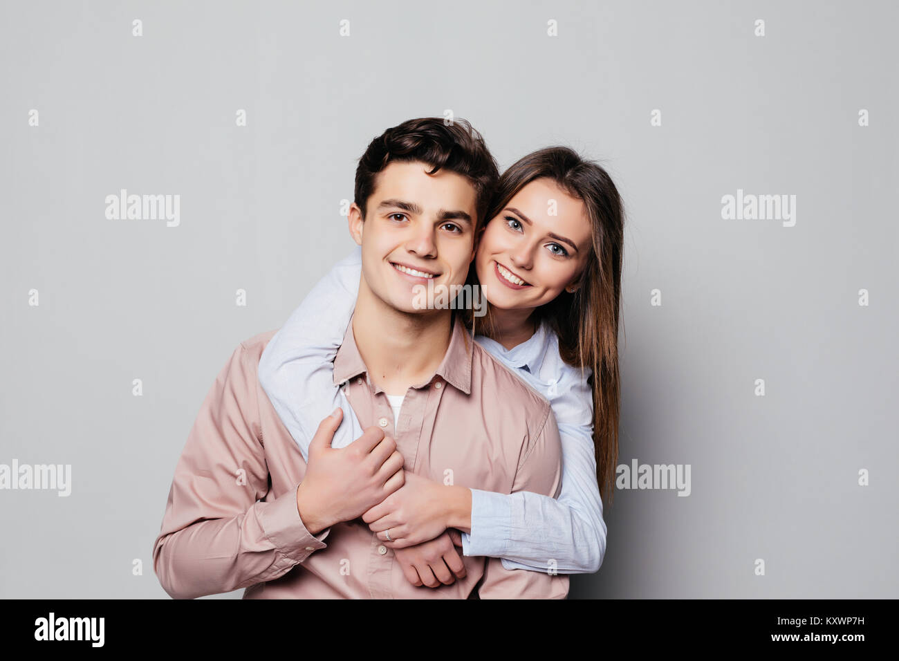 Portrait of a cheerful young couple hugging while standing and looking ...