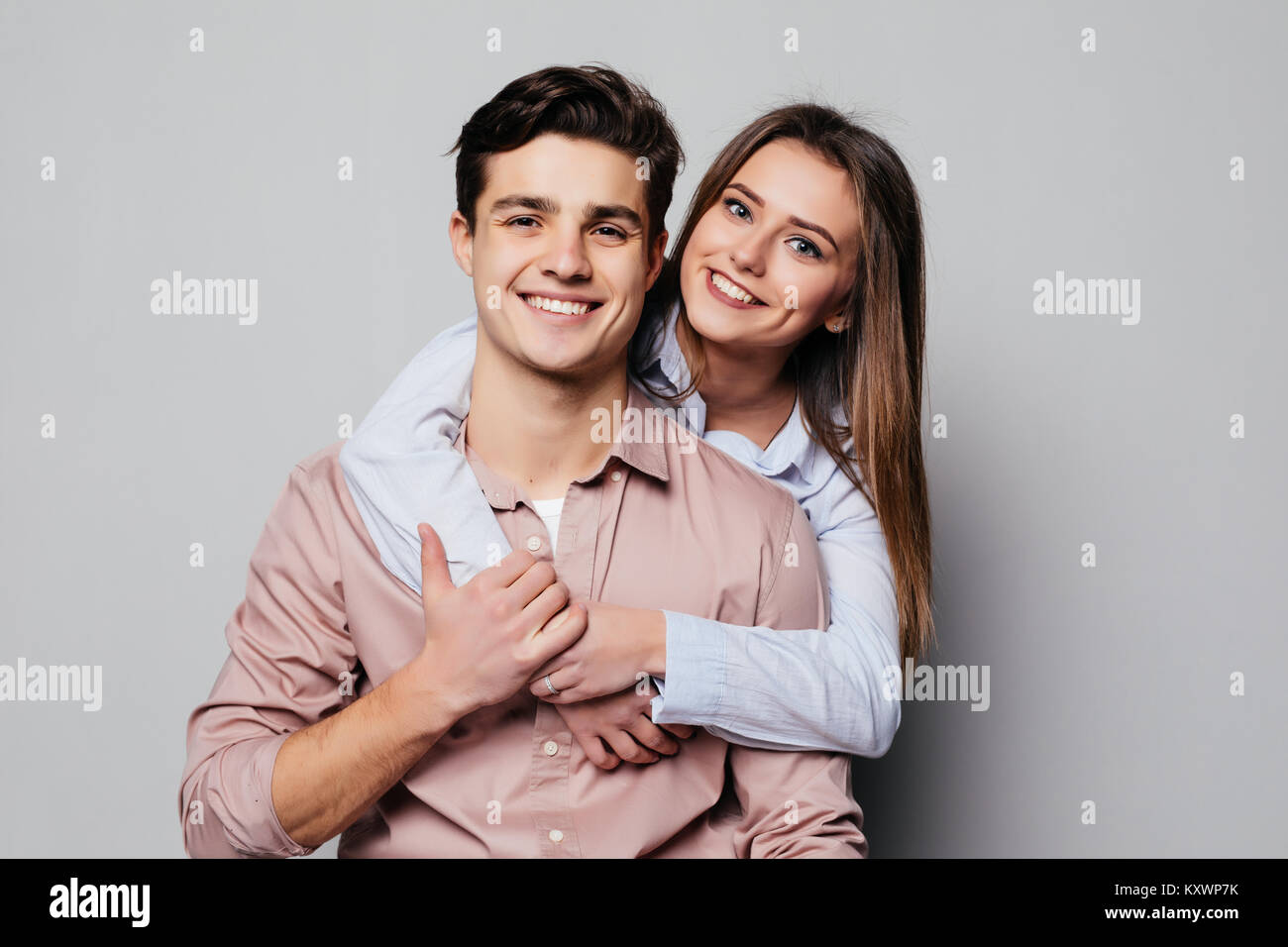 Portrait of a cheerful young couple hugging while standing and looking ...