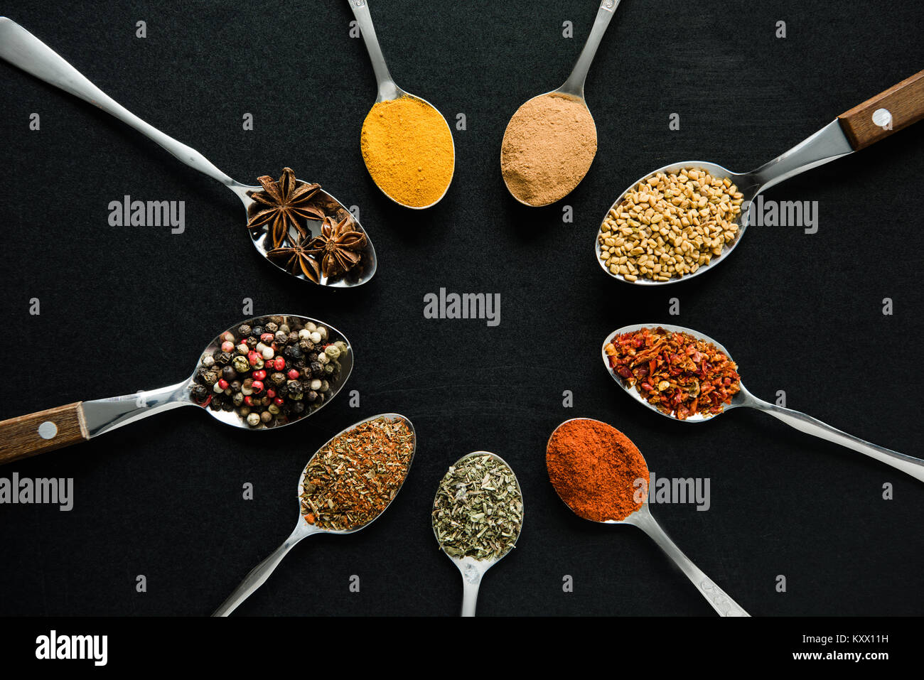 top view of various spices and herbs in metal spoons isolated on black Stock Photo