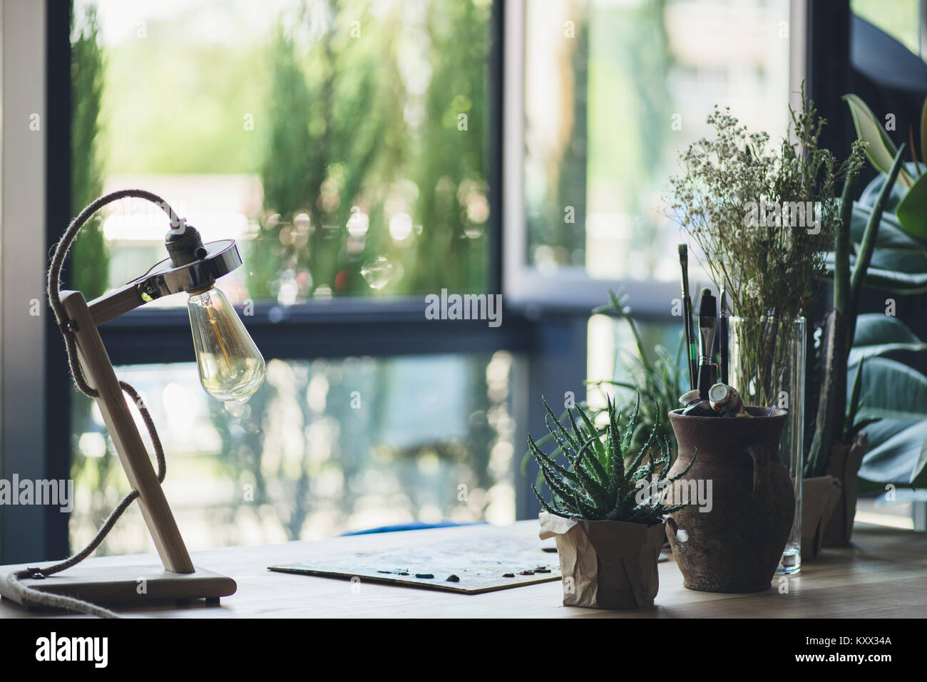 Group of potted green plants, drawing equipment and retro table lamp on workplace Stock Photo