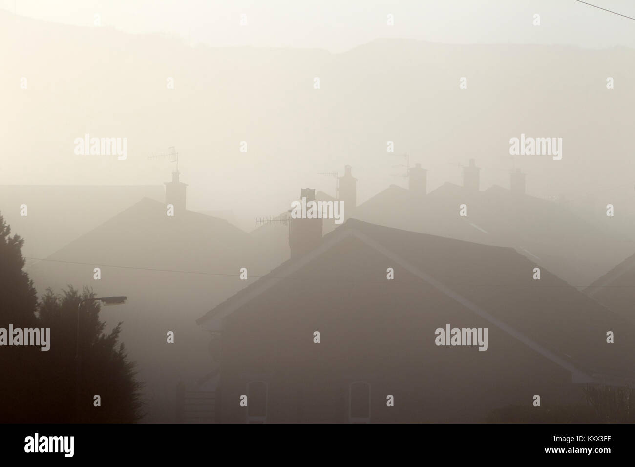 fog over residential homes with chimneys on a foggy day in the uk Stock Photo