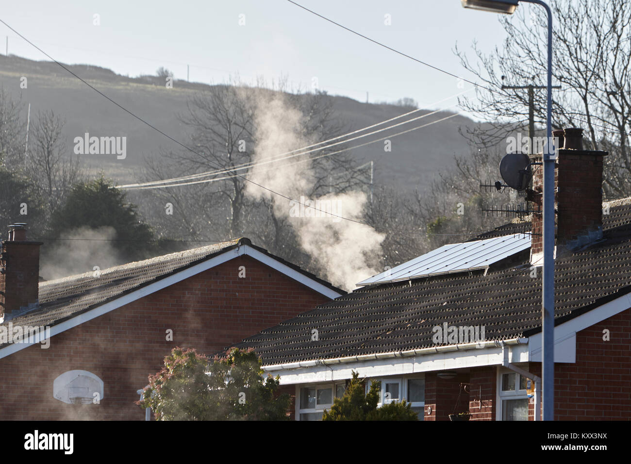 rooves drying and steam rising from heating system and solar panels on roof foggy day in the uk Stock Photo
