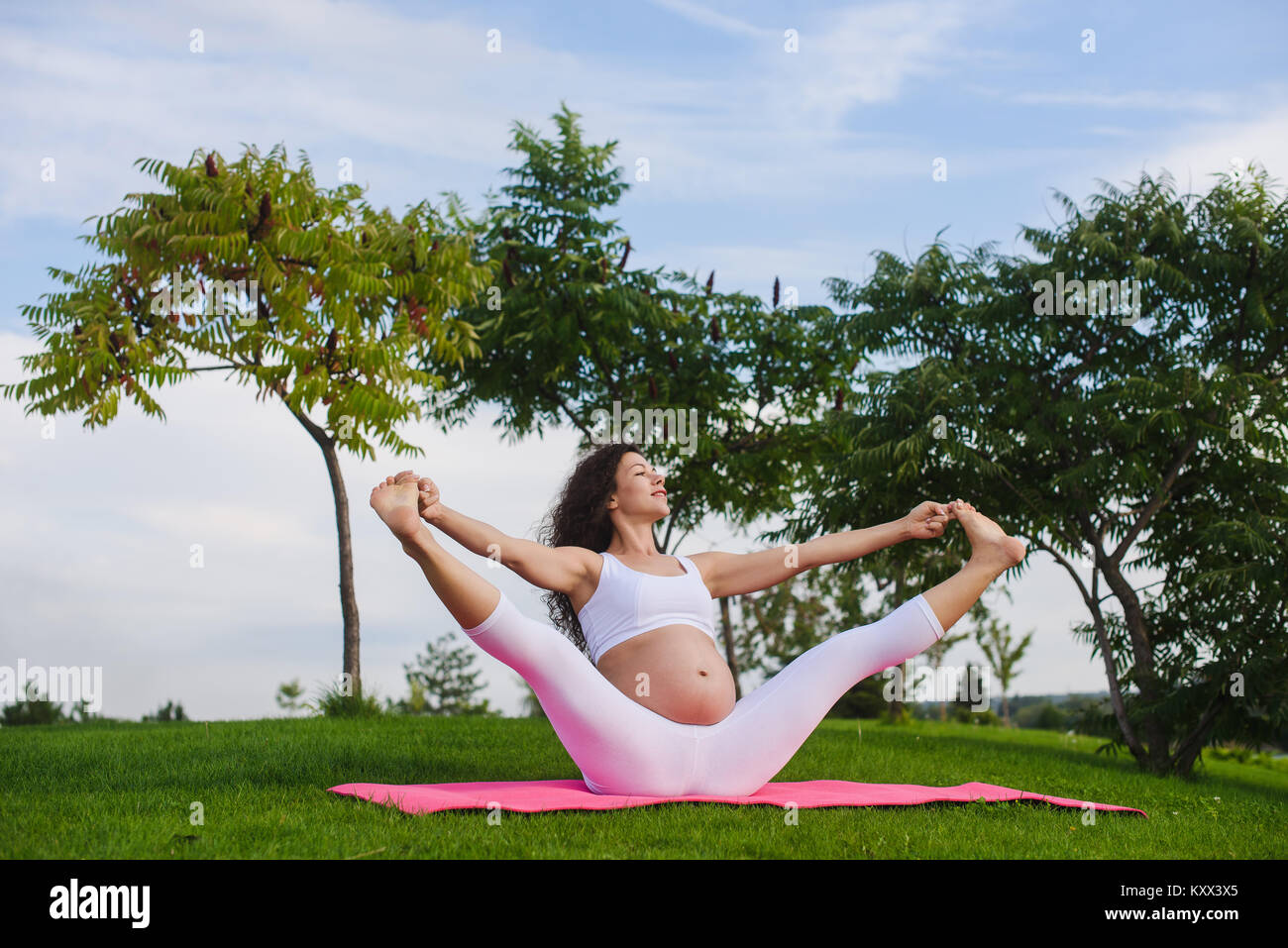 Pregnant woman doing yoga outdoors Stock Photo