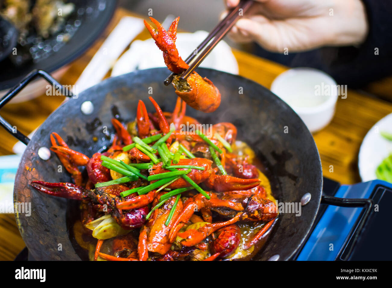 Chopsticks taking crayfish from spicy crayfish pot on the table Stock Photo