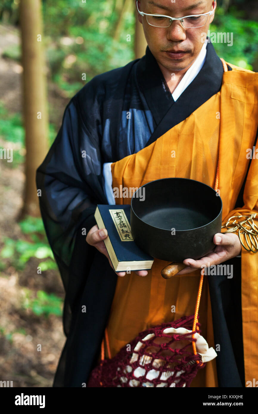Buddhist monk with shaved head wearing black and yellow robe, standing