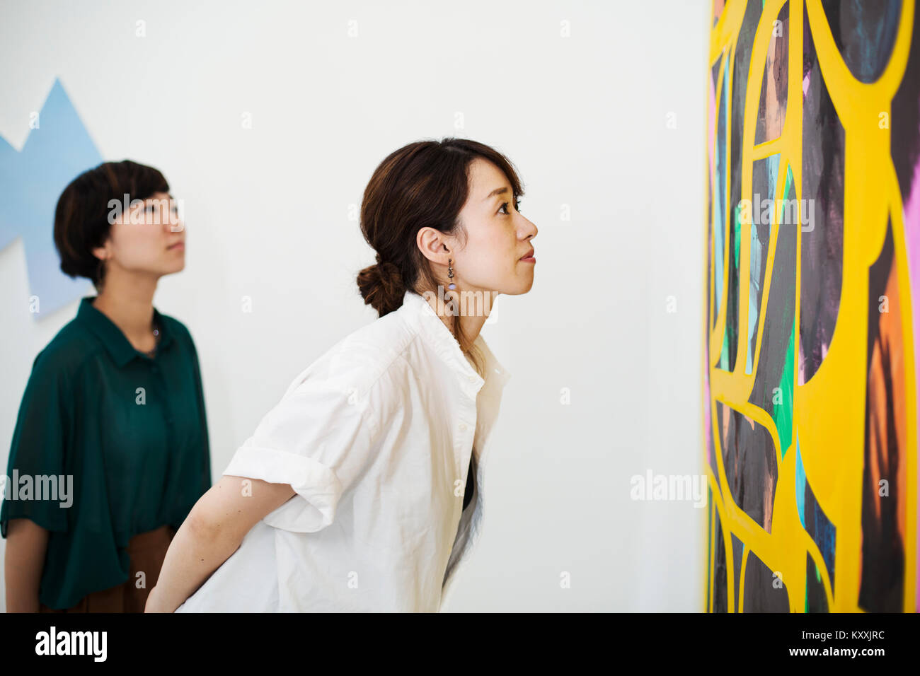 Two women standing in an art gallery, looking at an abstract modern ...