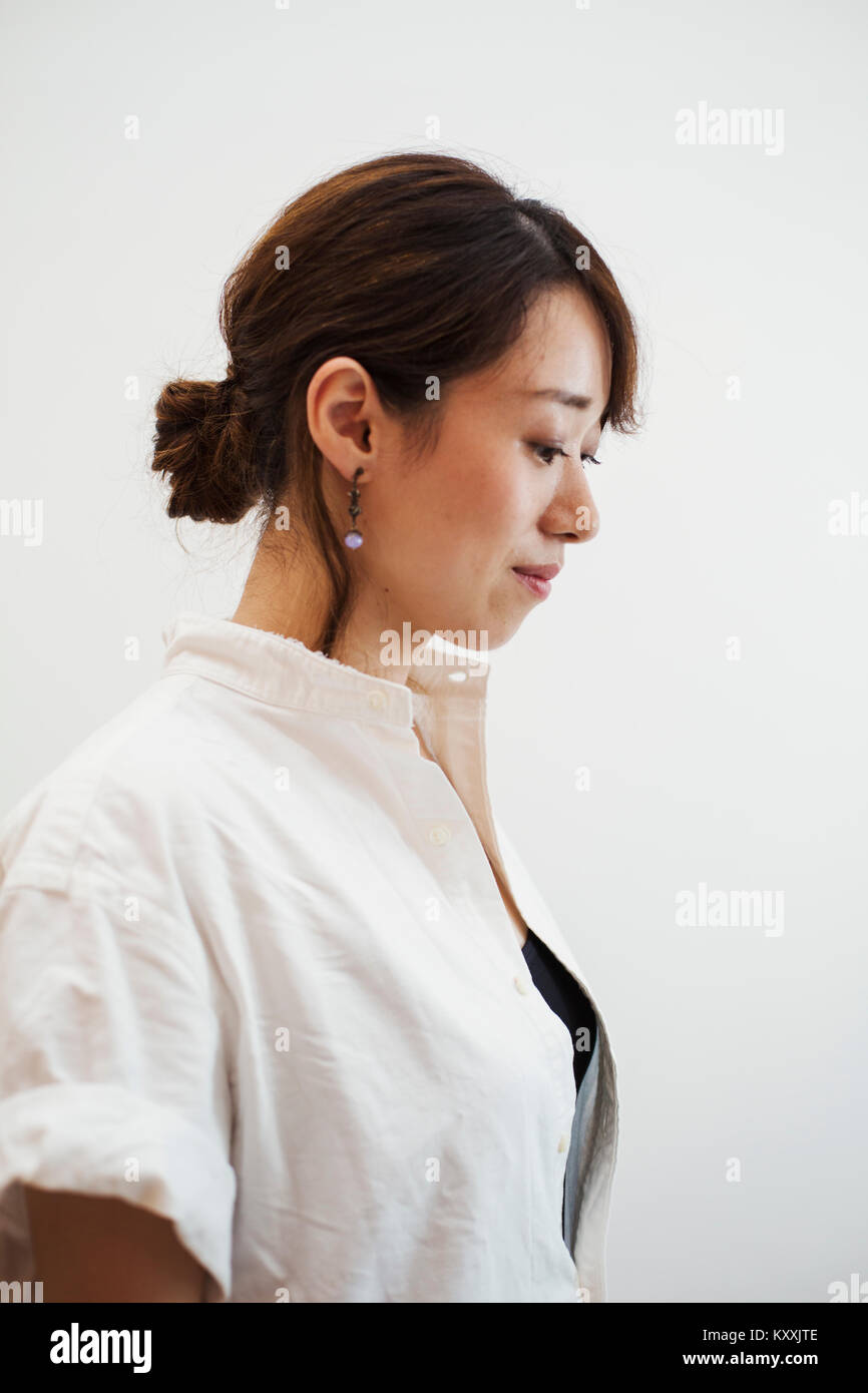 Profile view of woman with ponytail wearing white shirt standing in art gallery. Stock Photo