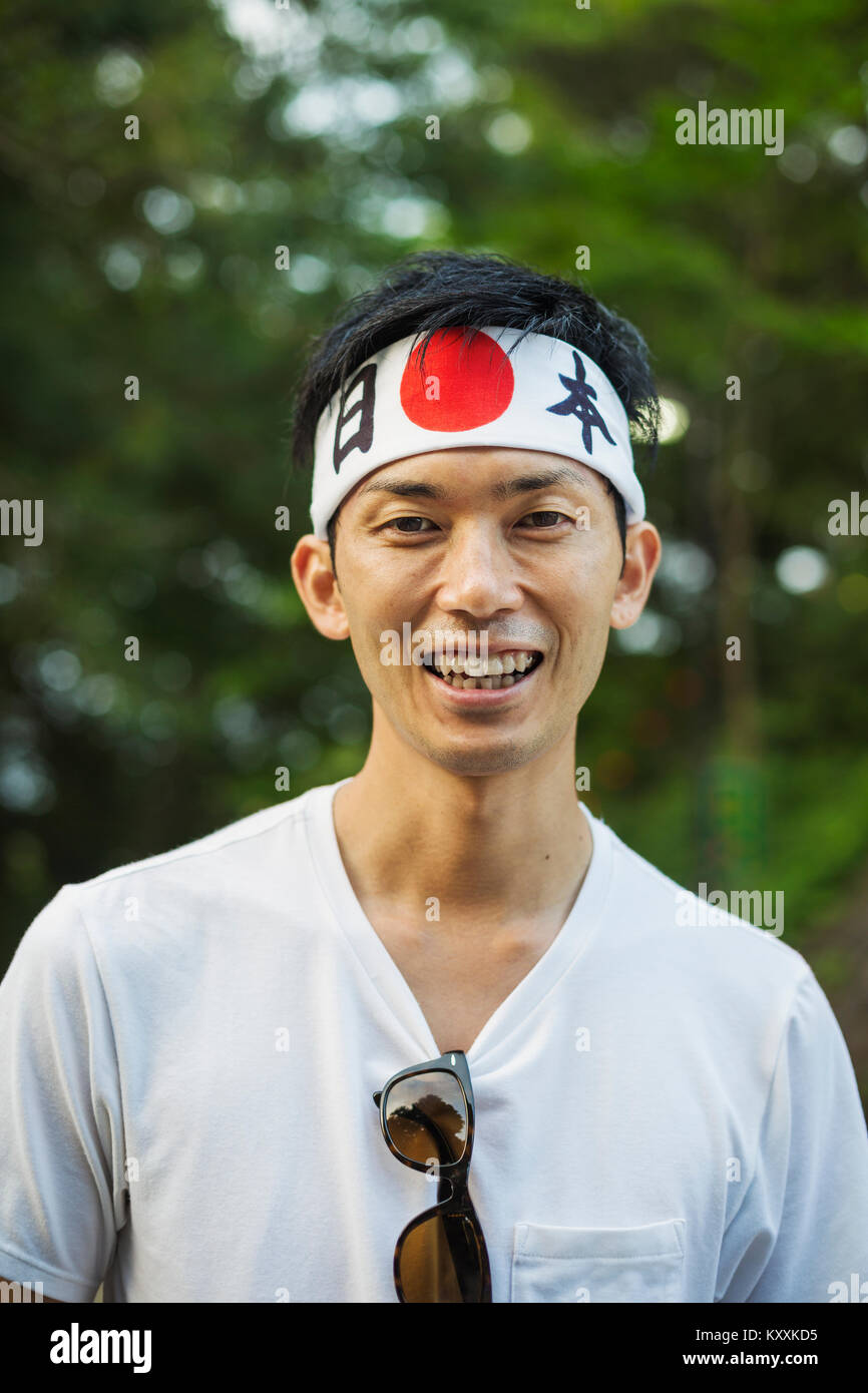 Portrait of man wearing headband with Japanese flag smiling at camera