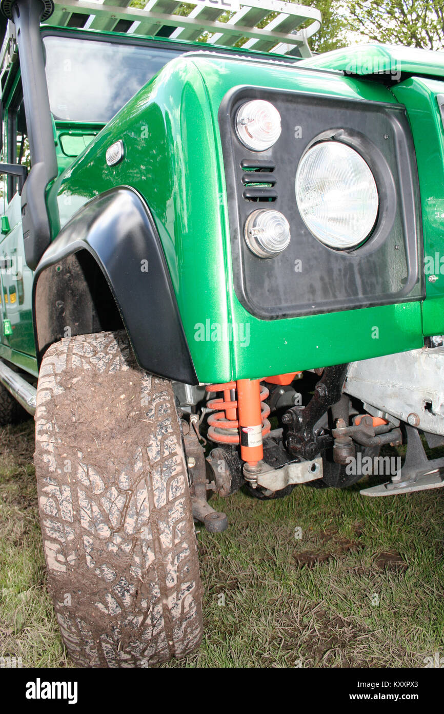 Green Land Rover Defender 90 with chunky tyres tires covered in mud prepared for expedition off roading green lane seen at Land Rover Show Stock Photo