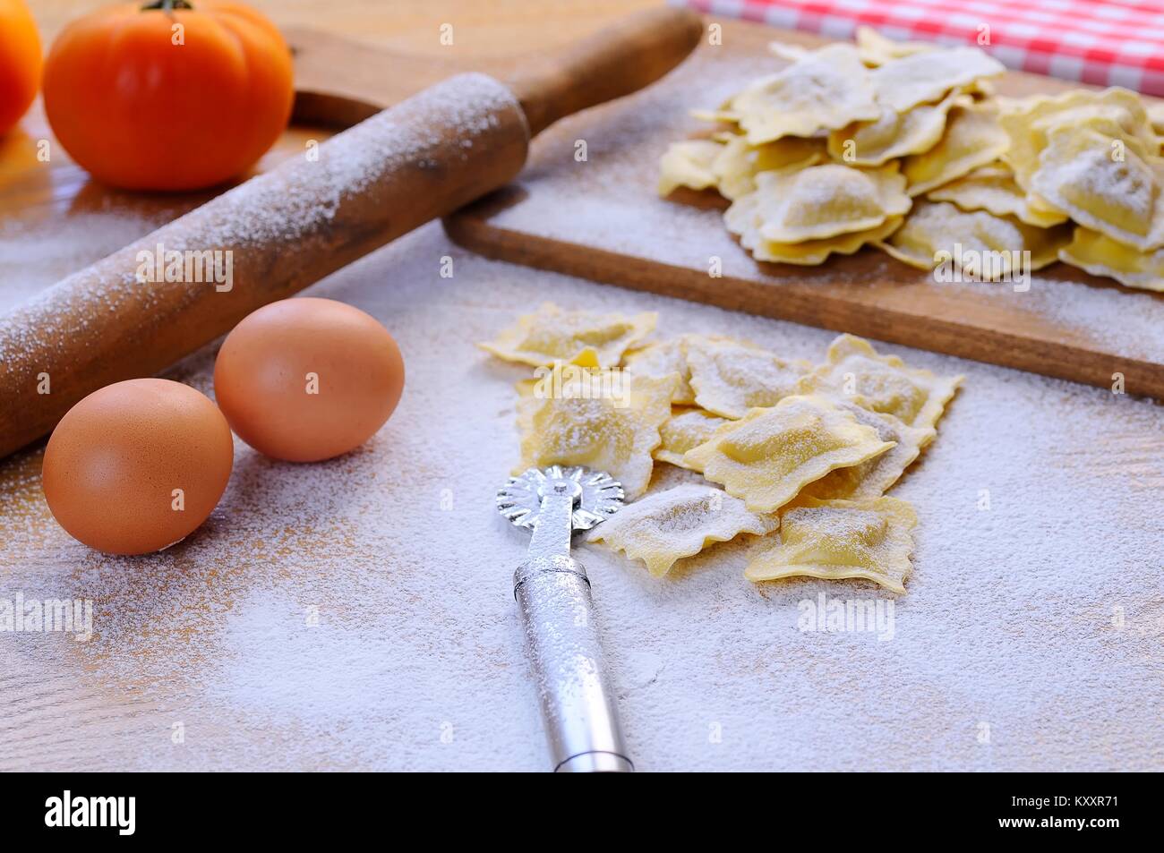 Uncooked vareniki on table covered with flour.Eggs, rolling pin. Stock Photo