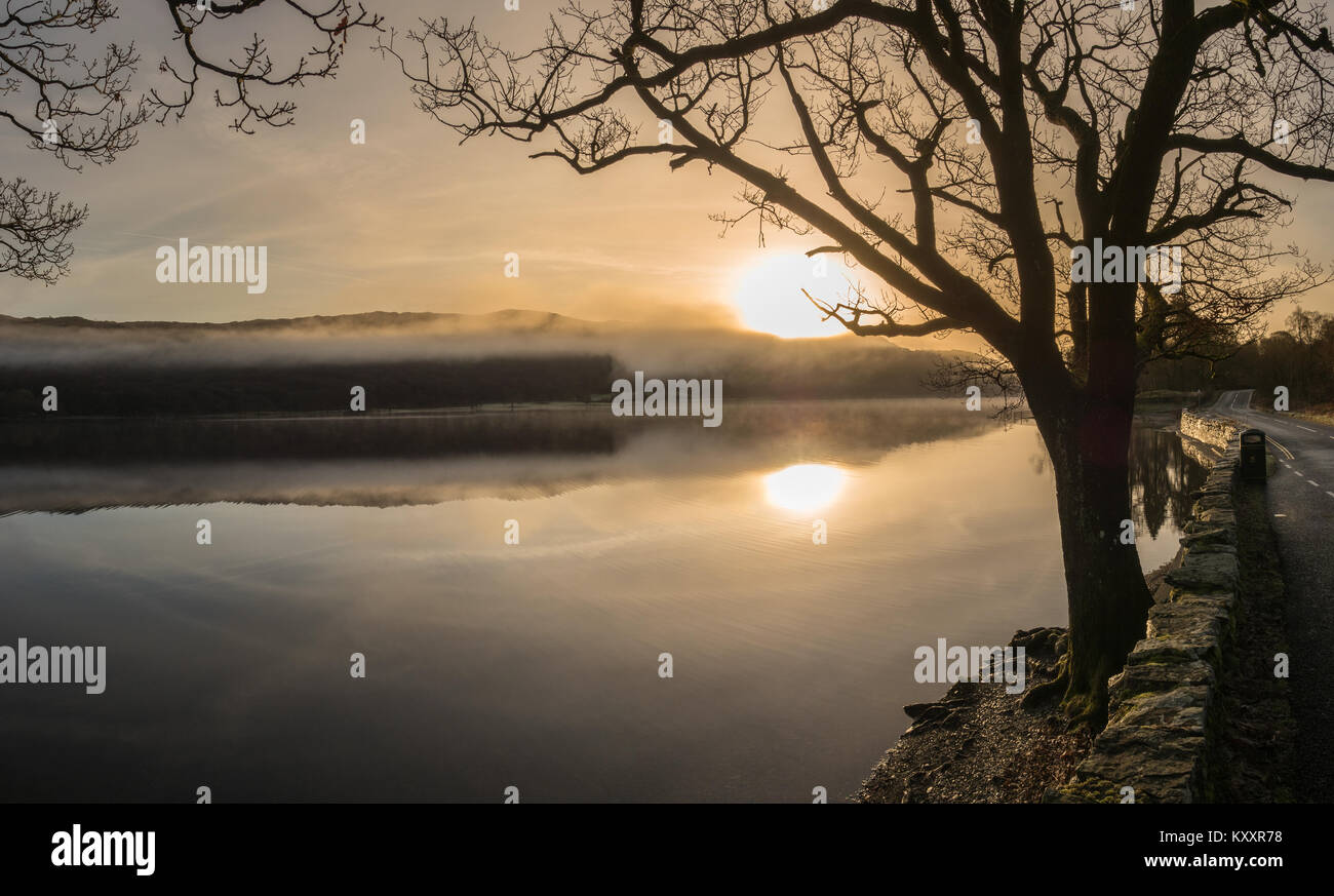 Morning mist rises on Coniston Water after a very cold and frosty night. Stock Photo
