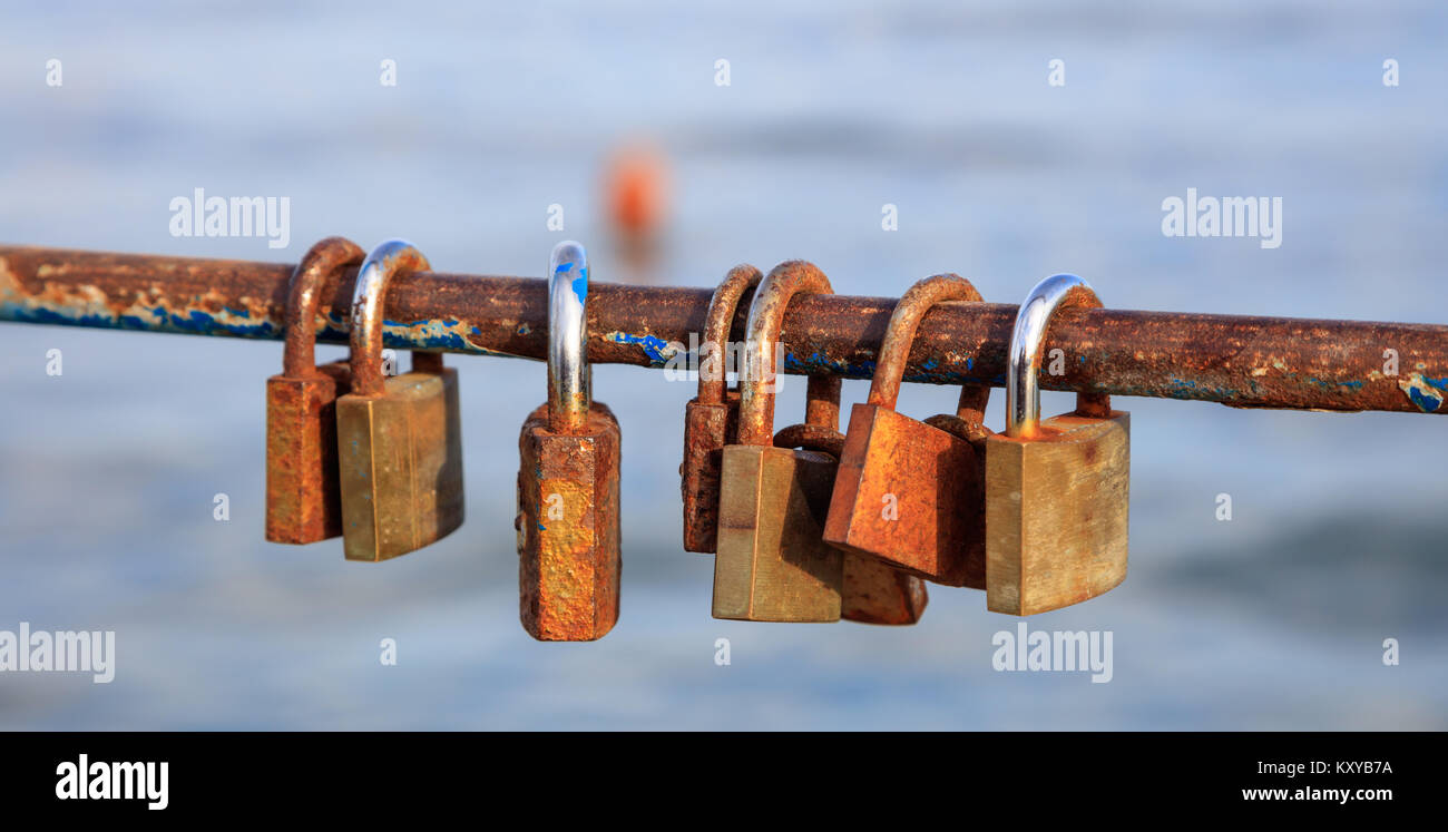 Rusty padlocks locks on peeled railing. Tradition for couple in love. Blur backdrop, closeup, detail Stock Photo
