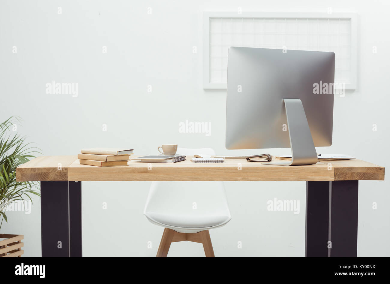 empty workplace with computer screen, notebooks and coffee cup in office Stock Photo