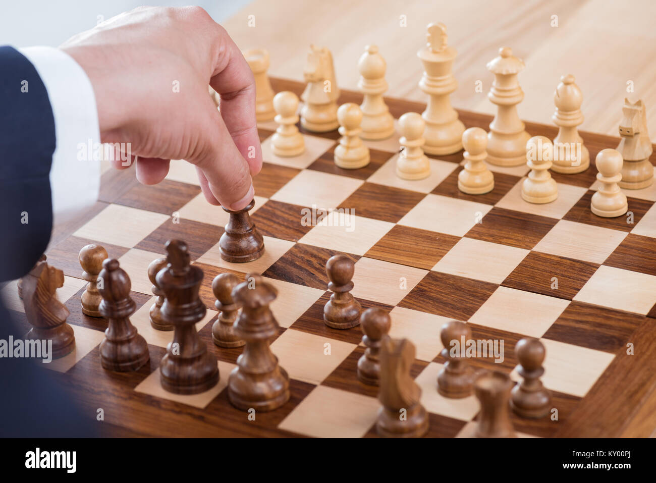 partial view of businessman holding chess figure while playing chess alone Stock Photo
