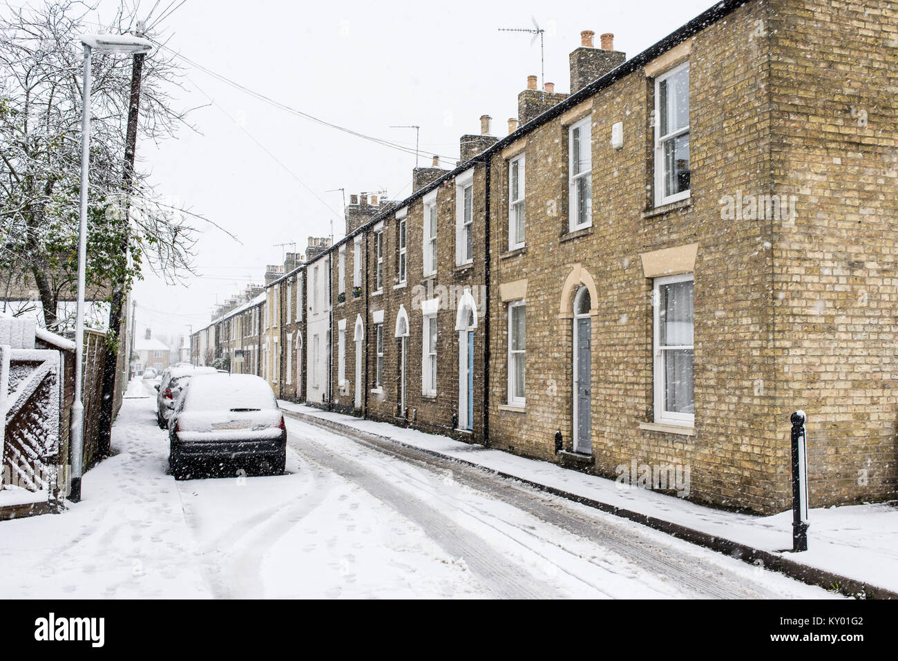 Row of restored period Georgian British townhouses in yellow bricks during heavy snow in winter with car parked in front on the local street covered i Stock Photo