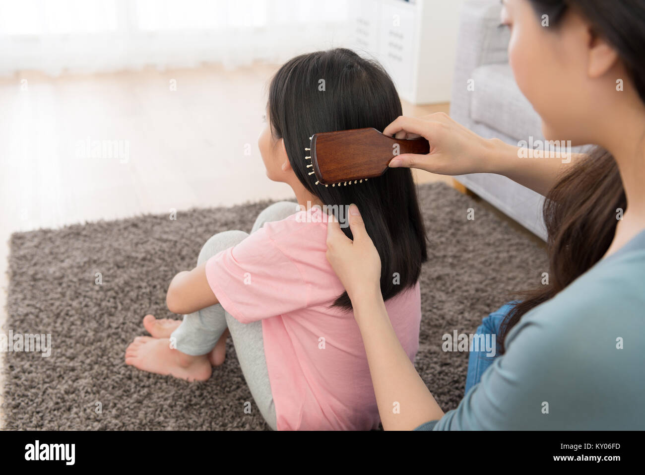 back view photo of young woman using brush combing little girl hair. Stock Photo