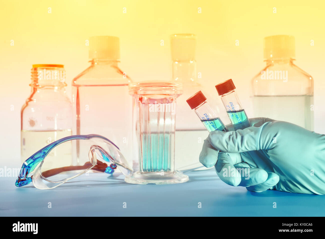 Two liquid samples in plastic vials in the hand of female scientist, scientific background in blue and orange Stock Photo