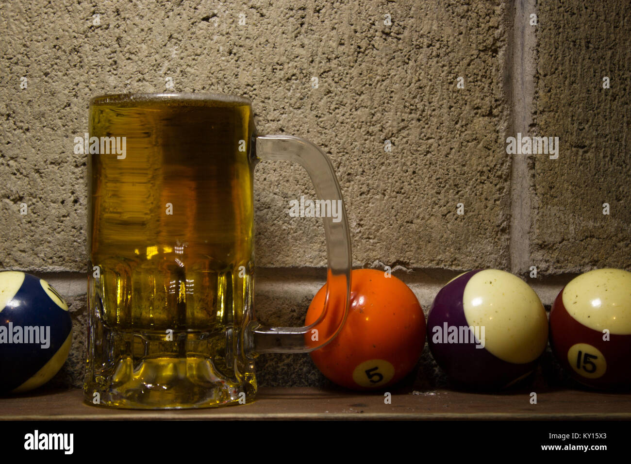 https://c8.alamy.com/comp/KY15X3/cold-beer-mug-on-a-next-to-several-colorful-billiard-balls-on-a-concrete-KY15X3.jpg