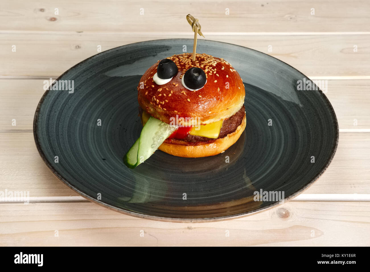 Funny meal for children. Burger in sahpe of face with pulled out tongue Stock Photo