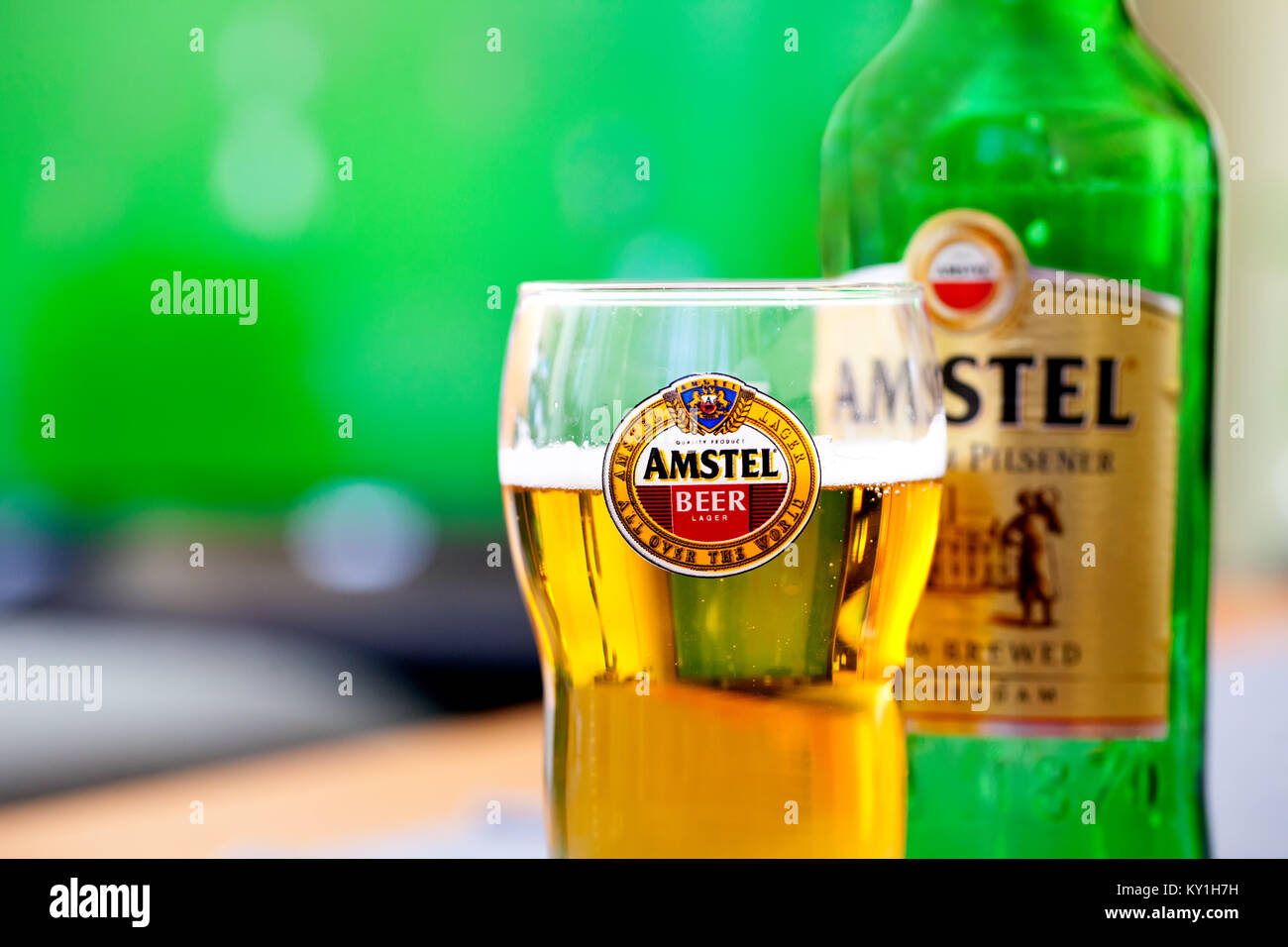 SOFIA, BULGARIA - MAY 08, 2017: Amstel glass and bottle -background of tv playing football game.Amstel Premium Pilsener is an internationally known br Stock Photo