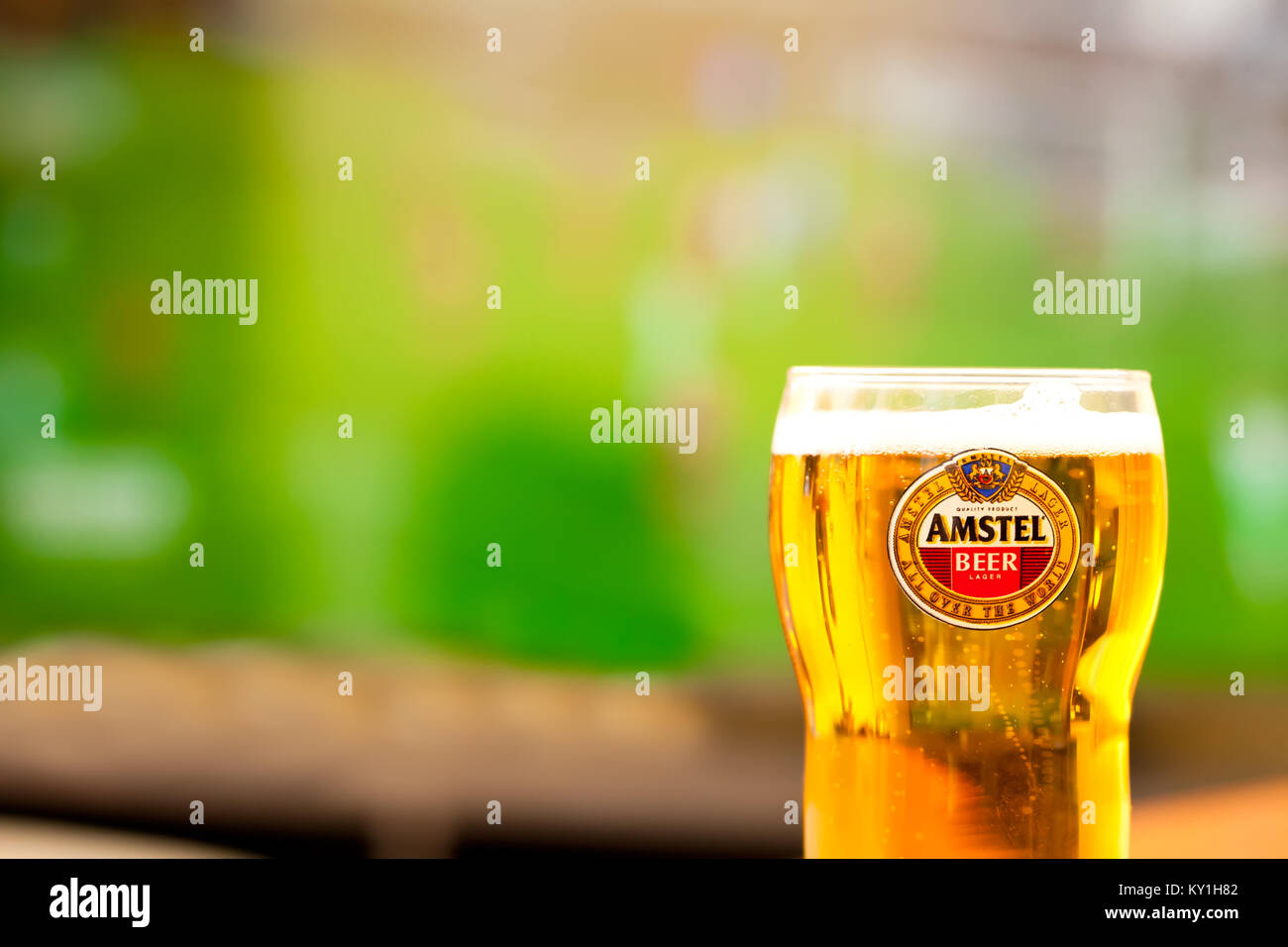 SOFIA, BULGARIA - MAY 08, 2017: Close-up Amstel glass full of beer -background of tv playing football game.Amstel Premium Pilsener is an international Stock Photo