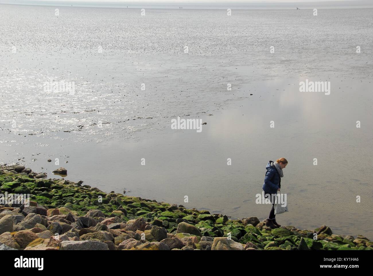 Romantic woman enjoys receding tide by the sea Stock Photo