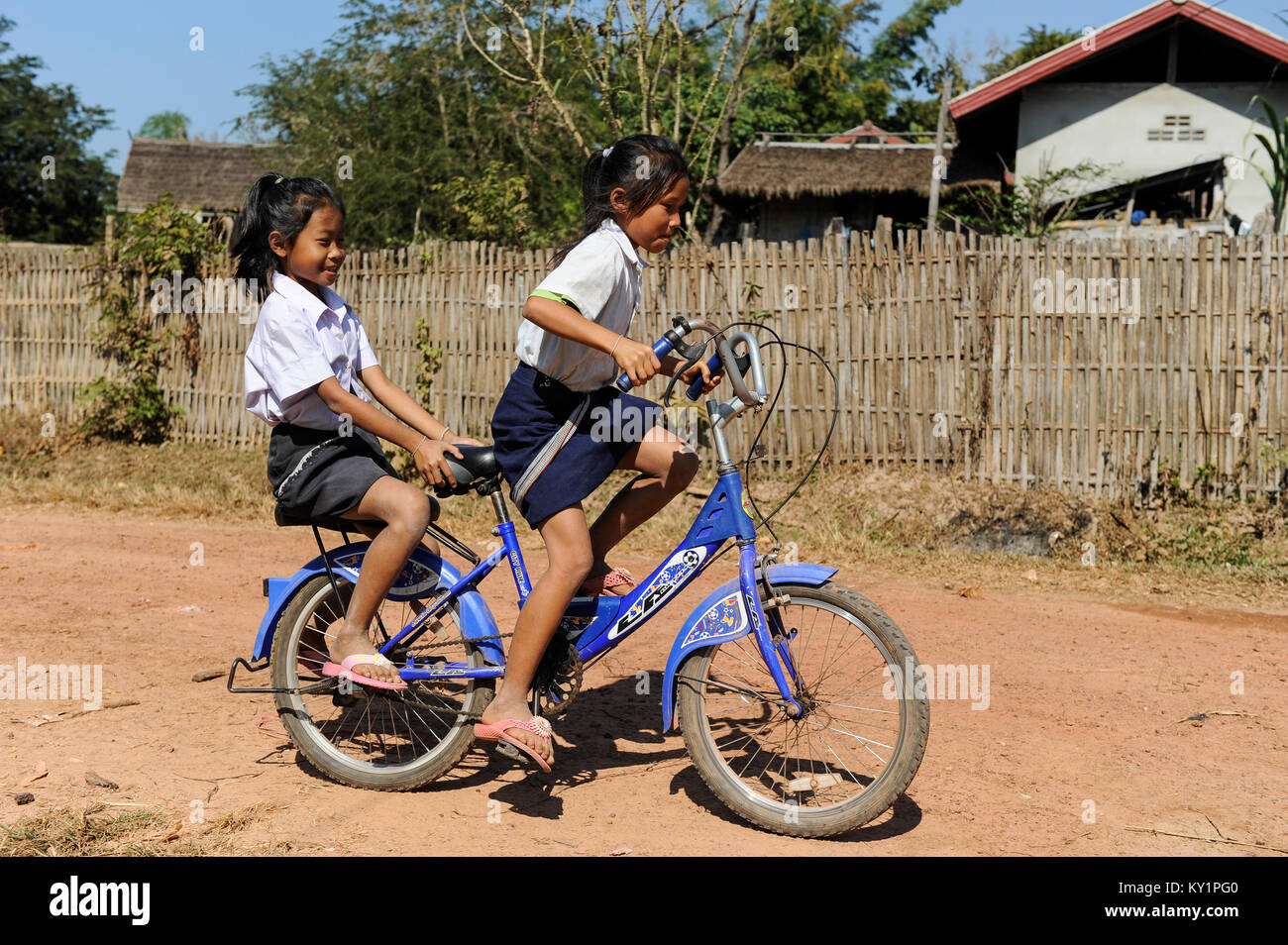 LAOS Province Vientiane, village Tham , two girls coming from school by bicycle / Kinder kommen mit dem Fahrrad von der Schule Stock Photo