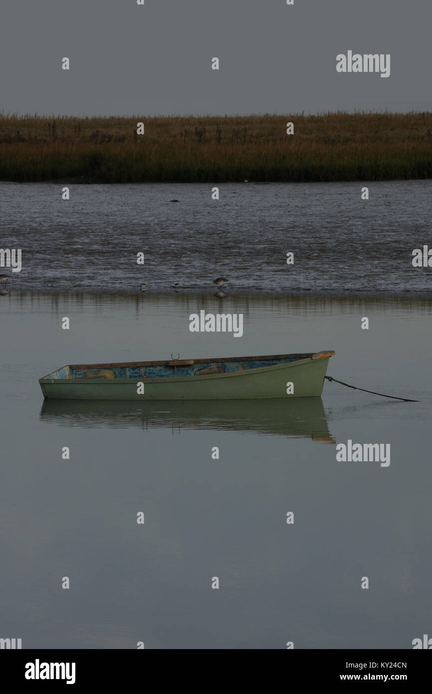 Wooden boat with reflection on water, reed banks in the background. Copy space top and bottom. Stock Photo