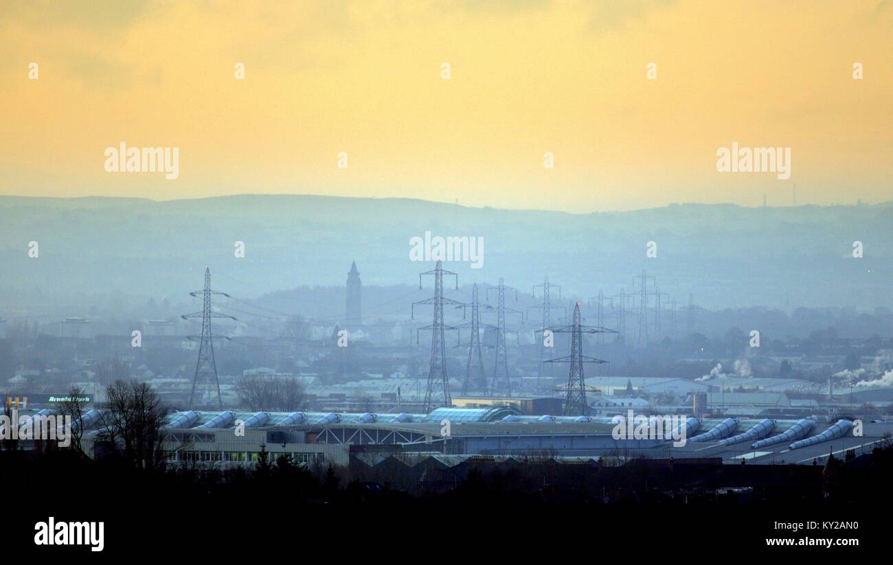 Glasgow, Scotland, UK 12th January.UK Weather: Bright dawn start to a misty morning with the promise of a sunny day over the south of Glasgow. The electricity pylons at Braehead arena stand beside the old Leverndale Hospital Water Tower in the distance Credit: gerard ferry/Alamy Live News Stock Photo