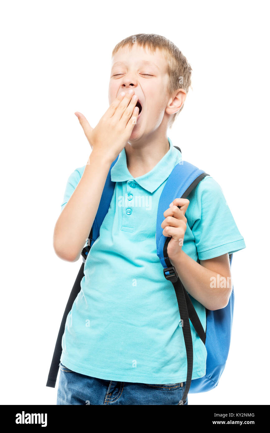 yawning schoolboy covers his mouth with his hand on a white background portrait isolated Stock Photo