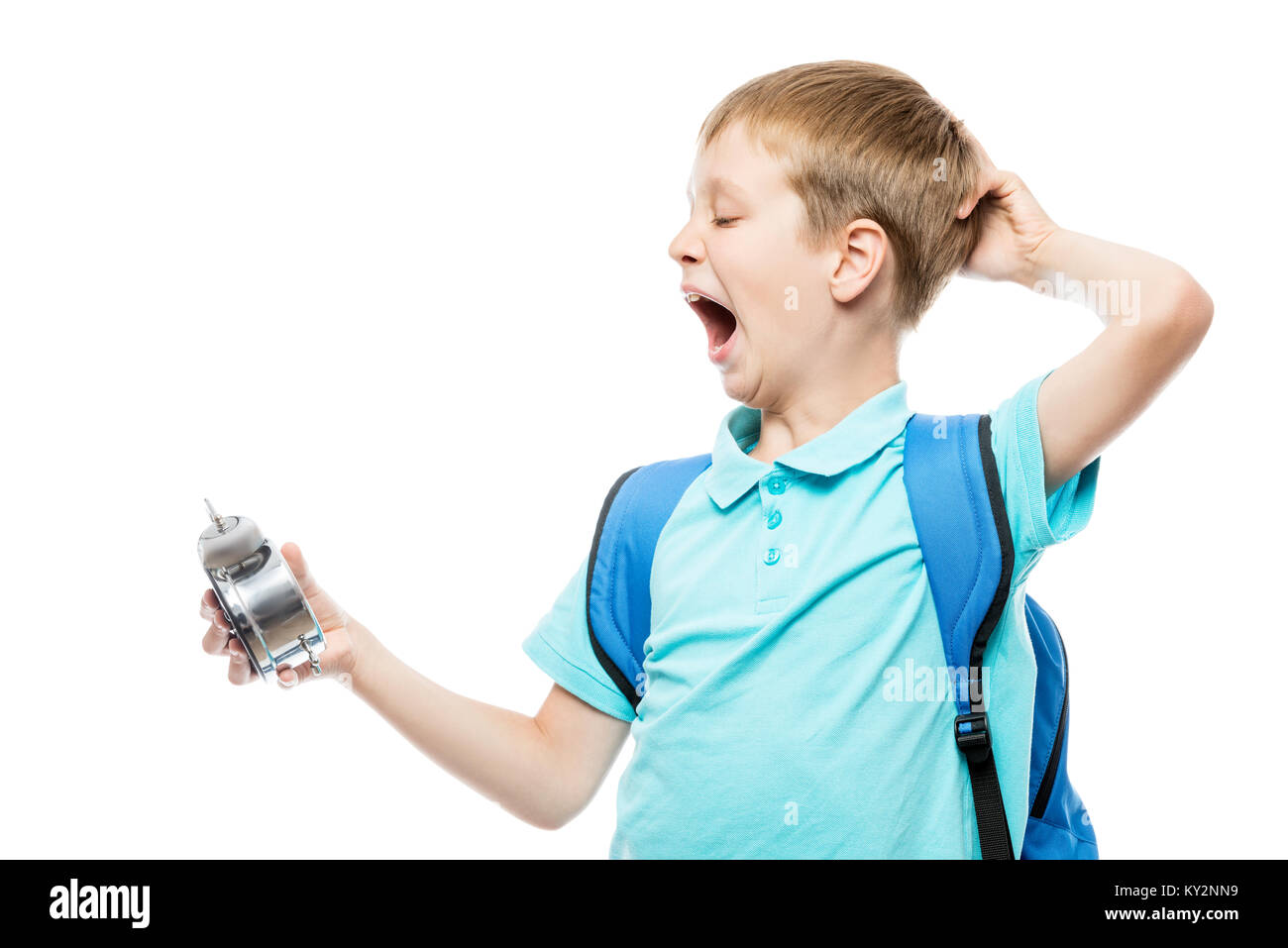 tired yawning schoolboy with an alarm clock on white background Stock Photo