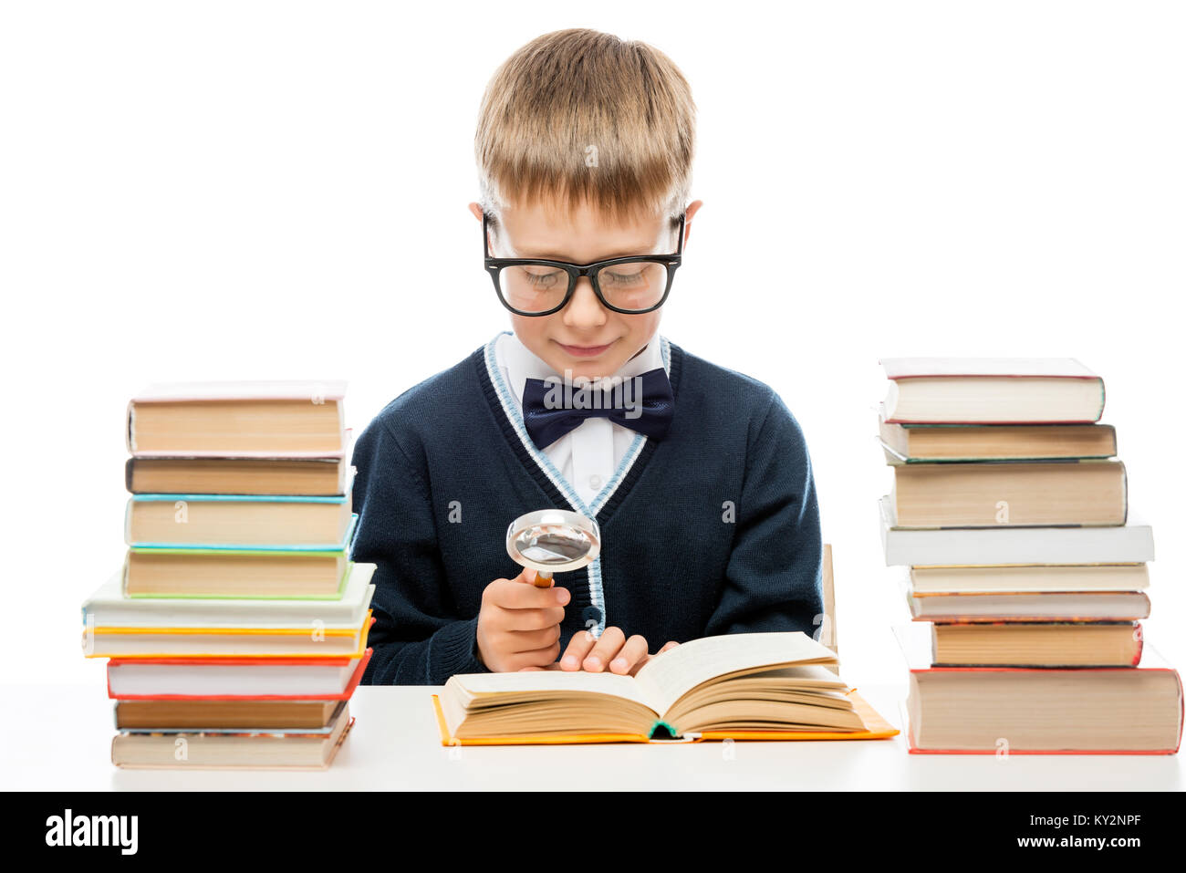 smart boy with glasses with a magnifying glass is considering the text of the book, portrait isolated Stock Photo