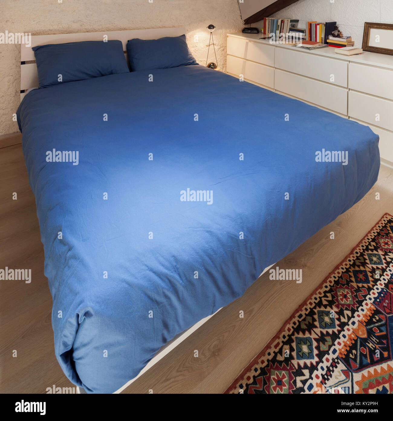 Bedroom of a loft, double bed with blue bedding Stock Photo Alamy