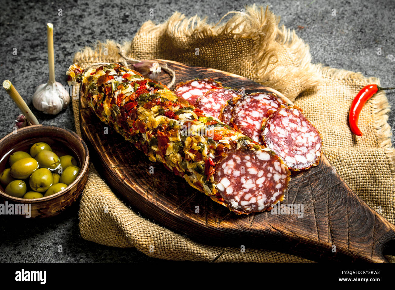 Salami of pork and beef with olives and spices. On a rustic background ...