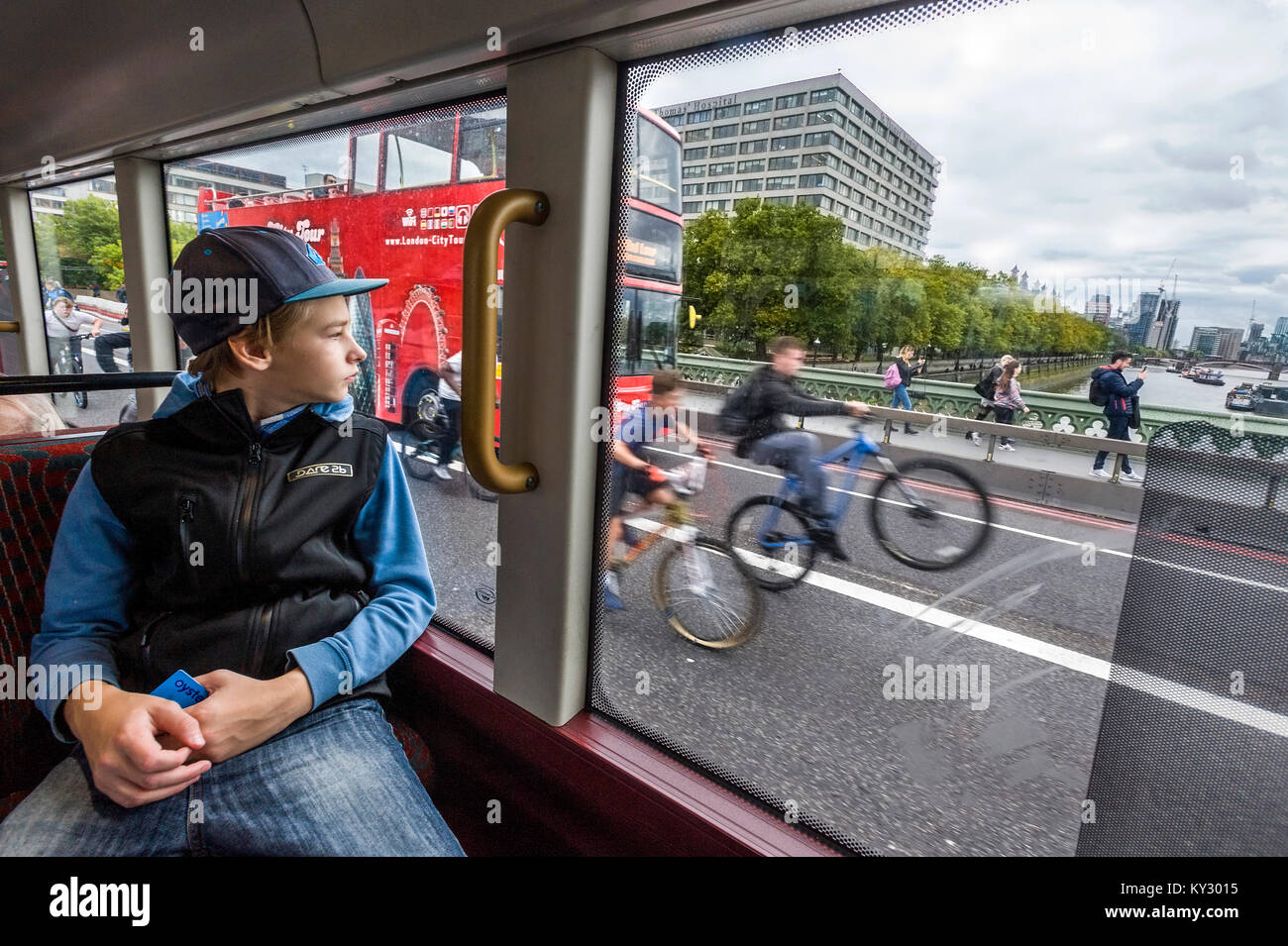 teeage boy sitting in the bus looking through the window watching bikers Stock Photo