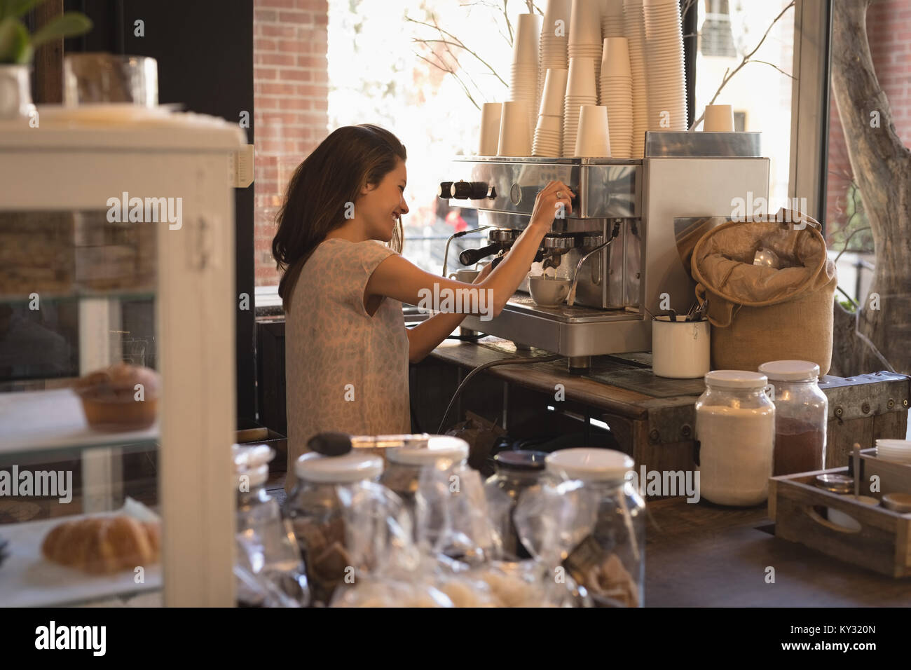 Smiling waitress making cup of coffee Stock Photo